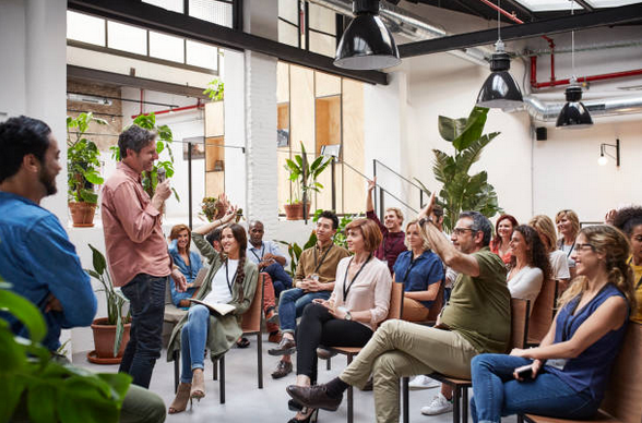 Réunion d'entreprise avec des salariés souriants et un cadre qui fait un discours