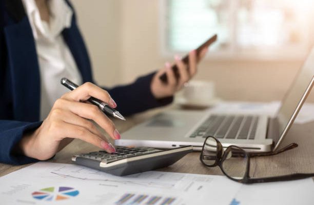 Femme qui tient les comptes d'une entreprises à l'aide d'une calculette