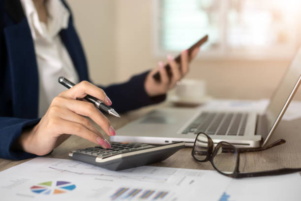 Femme qui tient les comptes d'une entreprises à l'aide d'une calculette