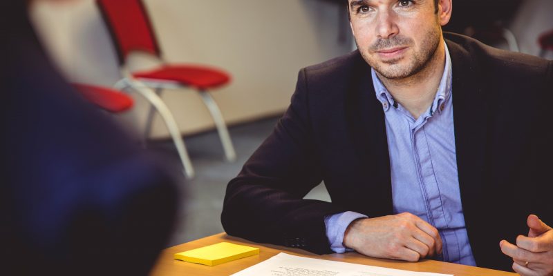 homme assis derrière un bureau avec des documents sur le bureau